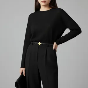 Detailed view of women's black leather belt featuring a chic geometric gold buckle accessory.