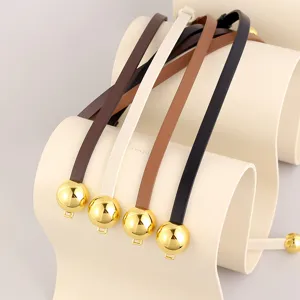 Women thin leather belt with gold spherical buckle detail for dress styling accessory.