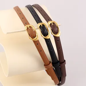 Detail view of minimalist thin leather belts in three colors with gold pin buckles.