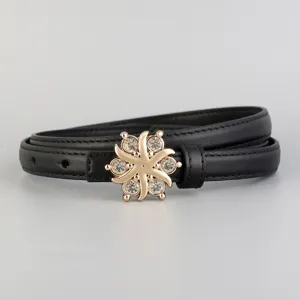 Close-up of slim black leather belt featuring a dazzling gold-tone rhinestone floral buckle.