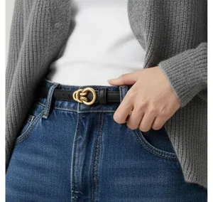 Women's slim black leather belt with elegant gold interlocking metal buckle for jeans.