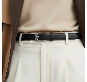 Close-up detail view of black leather belt with silver buckle worn on stylish white trousers.