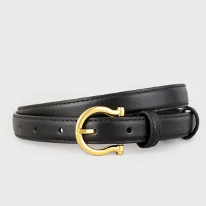 Close up of black leather belt with gold horseshoe metal buckle detail for women fashion style.