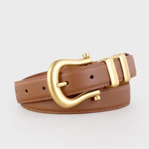 Close-up detail of brown leather women belt with unique gold horseshoe buckle and dual loops.