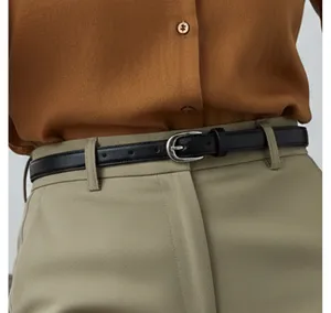 Minimalist black thin leather belt detail shot with classic silver pin buckle for women.