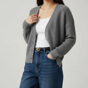 Women's grey knit cardigan paired with blue denim jeans and stylish leather belt.