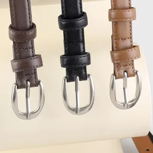 Close-up detail of slim women leather belts in brown, black, and tan with silver pin buckles.