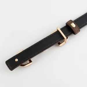 Close-up detail of women's black thin waist belt with gold buckle and brown loop.