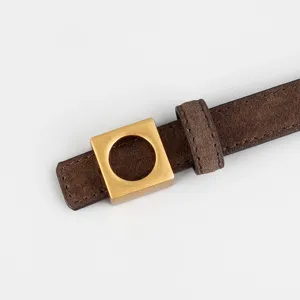 Close-up detail view of brown suede leather belt with modern square metal buckle and loop.
