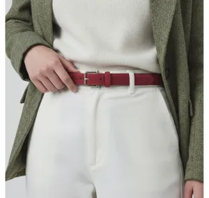 Close-up detail of a chic red leather belt with a silver buckle worn with white pants.