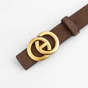 Ceinture femme en daim marron avec détail de boucle dorée à double anneau métallique vue gros plan.