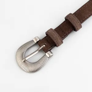 Close-up detail of brown suede leather women belt with vintage ornate silver metal buckle.