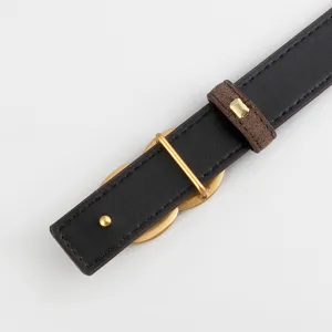 Close-up view of women's black leather belt with brown suede loop and gold hardware details.