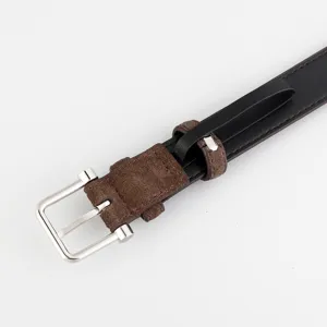 Close-up detail of women's black leather belt with brown suede loop and silver buckle.