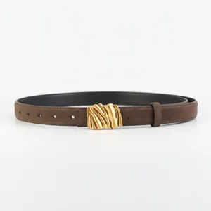Gros plan d'une ceinture femme en daim marron avec boucle dorée abstraite et finition mate chic.