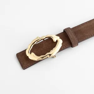 Detailed view of women's brown suede belt featuring a unique gold abstract metal buckle.