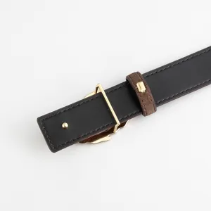 Close-up detail of women's black leather belt with gold metal buckle and brown loop.