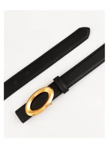 Close-up detail of black leather belt with sleek gold oval buckle, premium texture.