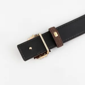 Detailed close-up of a black leather belt with brown suede loop and elegant gold buckle.
