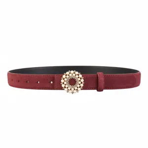 Close-up of women red suede leather belt with elegant pearl rhinestone round buckle detail.