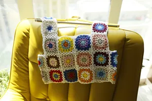Détail de gilet crocheté fait main granny square, haut d'été à motif floral coloré.