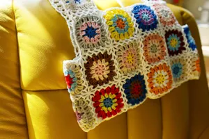 Gros plan sur un gilet crocheté main style Granny Square, détail de texture en laine colorée.