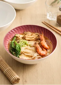 Detailed close-up shot of an exquisite ceramic noodle bowl with textured design on wood table.
