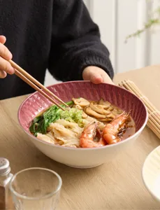 Detailed view of the elegant patterned ceramic bowl holding delicious noodles on a wooden table.