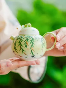 Closeup detail of the ceramic teapot featuring elegant willow and swallow art with lid decor.