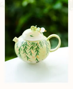 Elegant ceramic teapot in light green with willow leaf pattern and gold details for tea lovers.