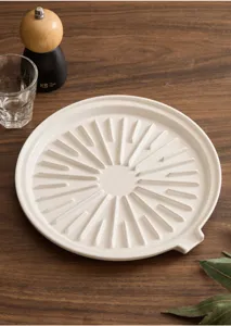 Ceramic oil drain plate detail featuring sunburst ribs and convenient pour spout on wooden table.
