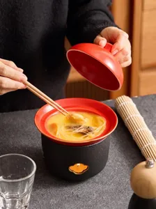 Keramik-Tontopf-Set mit rotem Deckel und schwarzem Sockel zum Erhitzen und Kochen.