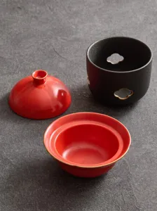 Detailansicht des Keramik-Wärmetopf-Sets mit rotem Schöpfer, Deckel und schwarzem Sockel.