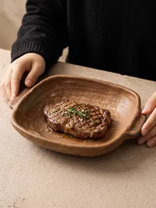 Close-up detail of the rustic ceramic double-handled plate showing its unique glazed texture.
