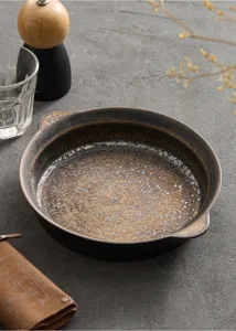 Diepe keramische schaal met gouden glazuur en dubbele oren, ideaal voor pasta en bakken.
