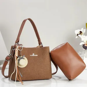 Detail view of brown herringbone pattern women handbag with cute hat pendant and matching pouch.