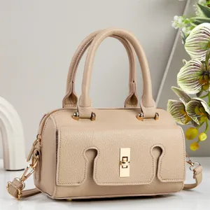 Chic light brown leather crossbody bag with dual top handles and gold turn-lock clasp.
