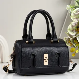 Close-up detail of a black leather handbag featuring gold-tone hardware and unique lock.