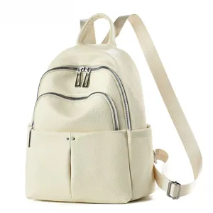 Détail de sac à dos en cuir crème montrant les poches zippées et les bretelles solides.