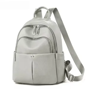 Detail du sac a dos en cuir gris avec poches zippees sur le devant et bretelles reglables.