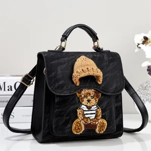 Stylish black PU leather backpack handbag featuring a cute knit bear patch and beanie design.