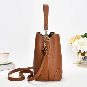Braune Leder-Textur Eimer-Tasche Detail zeigt Griff Metall Hardware und Schultergurt.