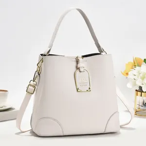 Schickes beige Leder Eimerbeutel Detail mit Goldbeschlägen und stylischem Front Metalllogo.