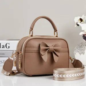Bruine handtas crossbody tas van leer met schattige strik en gouden metalen details.