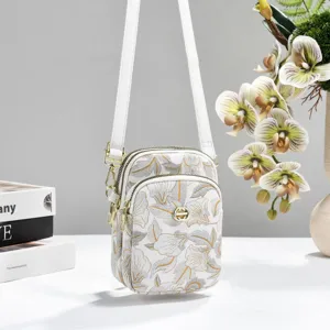 Close-up of the floral embroidered mini crossbody phone bag with dual-layer gold zip details.