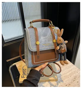 Vintage denim college backpack detail view, casual retro two-way shoulder bag with rabbit charm.
