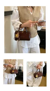 Detailed view of a vintage brown Boston handbag with floral charm, lifestyle outfit matching.