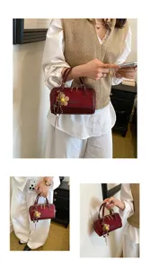 Burgundy suede boston bag for women, chic commuter shoulder handbag with floral charm.