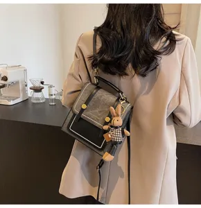 Detailed back view of vintage college style mini backpack with cute rabbit charm on coffee table