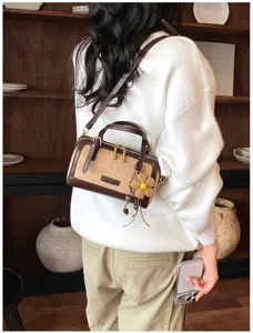 Detail view of trendy contrast mini Boston shoulder bag detail with cute floral charm decor.